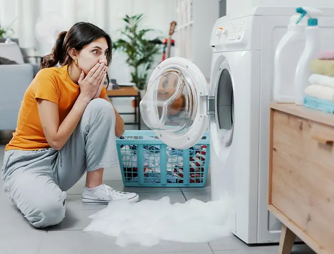a woman looking at her washing machine flooding