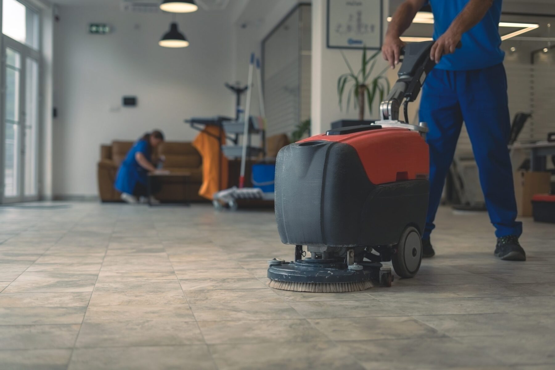 Cleaner cleans hard floor with scrubber machine while other clea professional tile cleaning